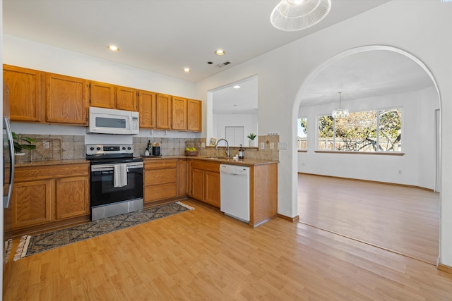 kitchen with white appliances, tasteful backsplash, light countertops, pendant lighting, and a sink