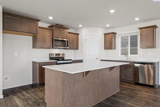 kitchen with appliances with stainless steel finishes, a center island, sink, and dark hardwood / wood-style flooring