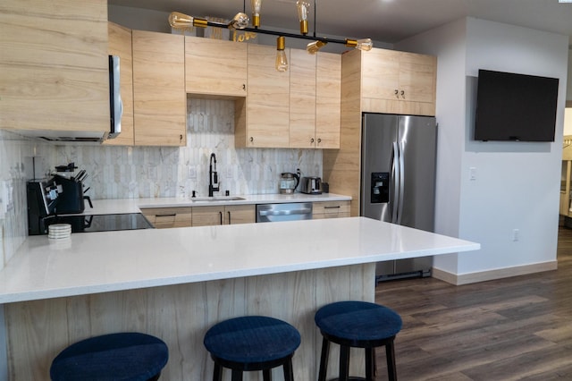 kitchen with appliances with stainless steel finishes, a kitchen breakfast bar, light brown cabinetry, and sink