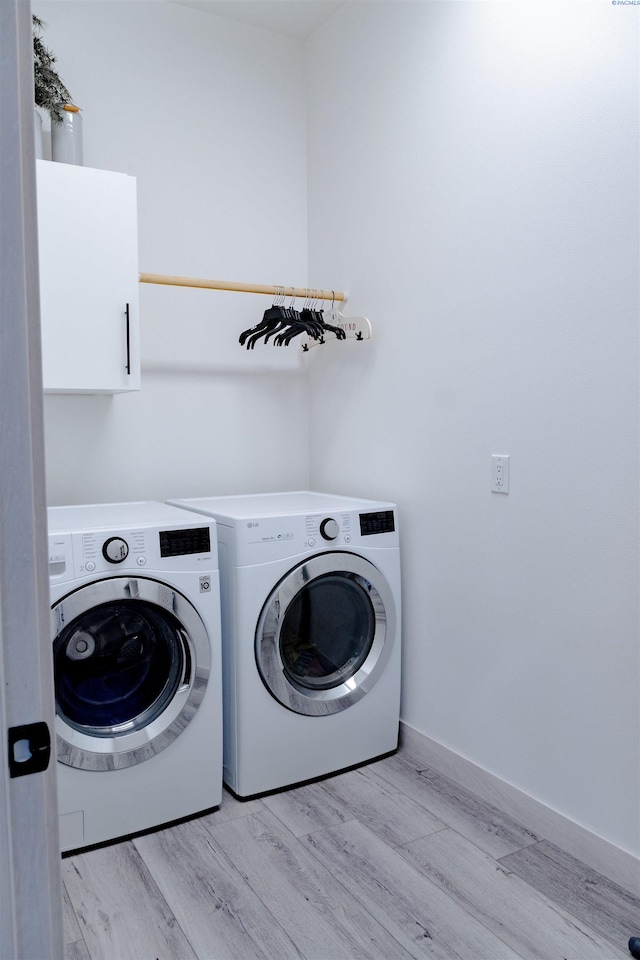 washroom featuring cabinets, separate washer and dryer, and light hardwood / wood-style floors