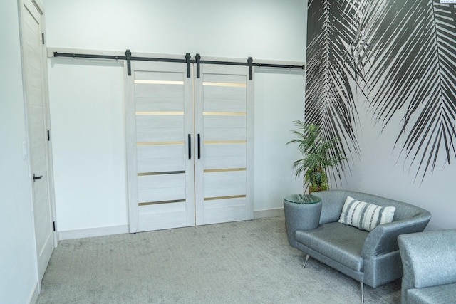 sitting room featuring a barn door and light colored carpet