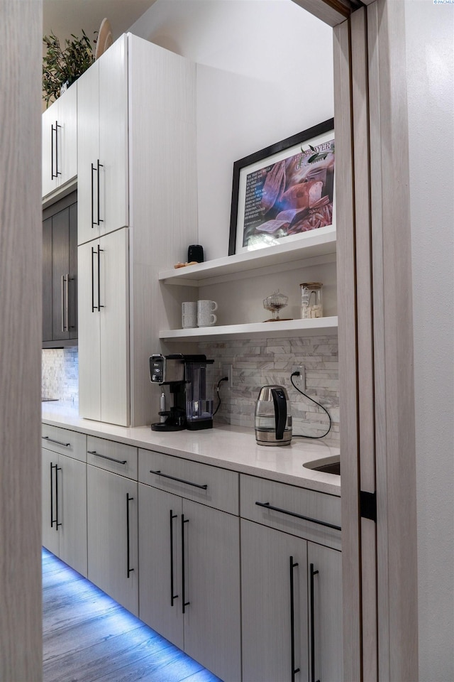 bar featuring tasteful backsplash, gray cabinets, and light hardwood / wood-style flooring