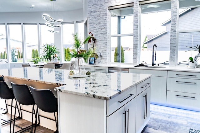 kitchen featuring light stone counters, sink, a center island, and light wood-type flooring