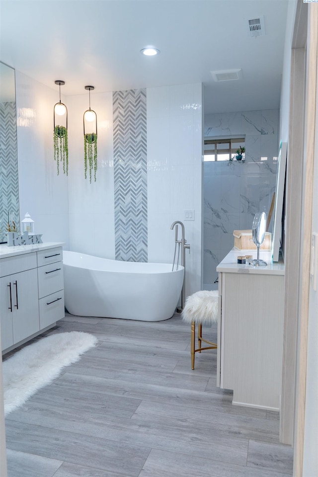 bathroom with vanity, hardwood / wood-style floors, and a bathtub