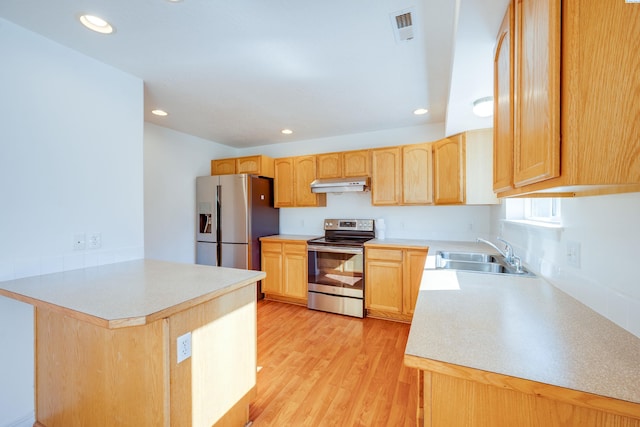 kitchen featuring a peninsula, light brown cabinetry, a sink, under cabinet range hood, and appliances with stainless steel finishes