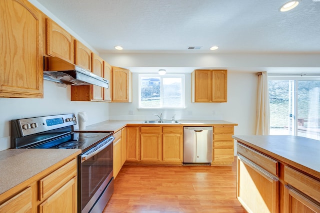 kitchen featuring visible vents, a sink, under cabinet range hood, appliances with stainless steel finishes, and light wood-type flooring