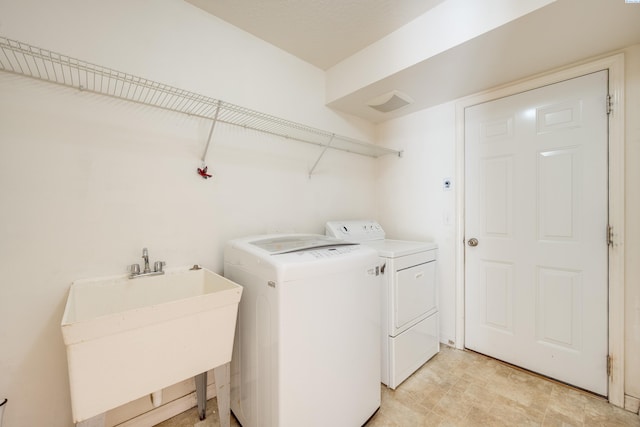 washroom with a sink, laundry area, and washer and clothes dryer