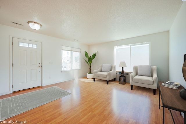 entrance foyer with visible vents, a textured ceiling, and wood finished floors