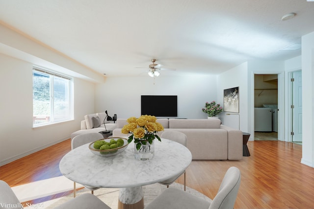 living room with baseboards, light wood-style floors, ceiling fan, and washer and clothes dryer