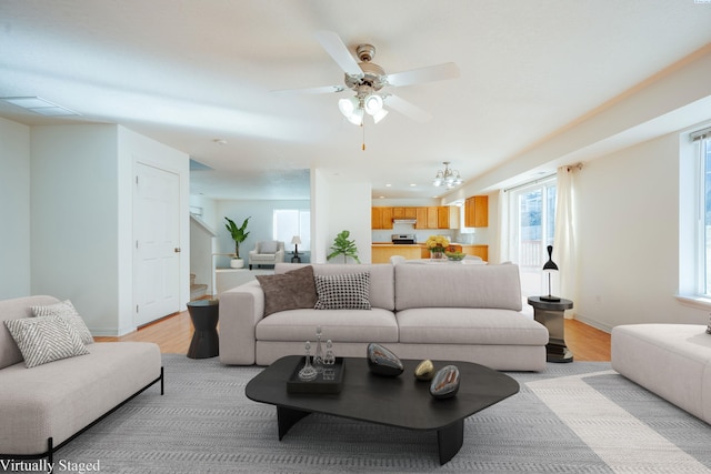 living area with visible vents, baseboards, light wood-type flooring, and ceiling fan