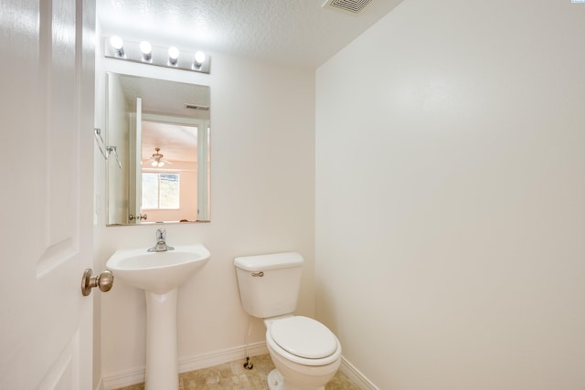 bathroom with visible vents, baseboards, toilet, and a textured ceiling