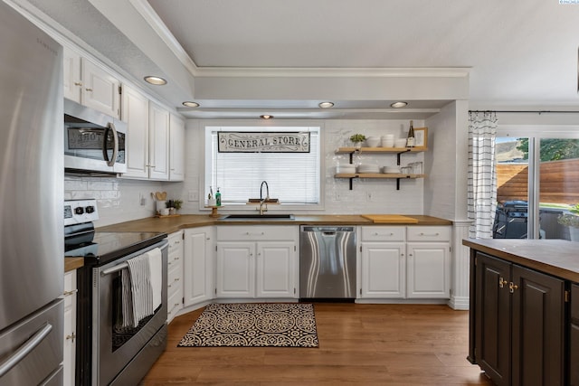 kitchen featuring appliances with stainless steel finishes, white cabinets, a sink, and wood finished floors