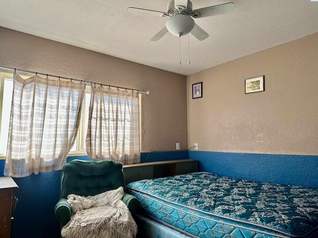 bedroom featuring a textured wall, a textured ceiling, and ceiling fan