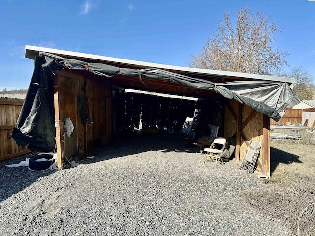 exterior space with an attached carport, gravel driveway, and fence