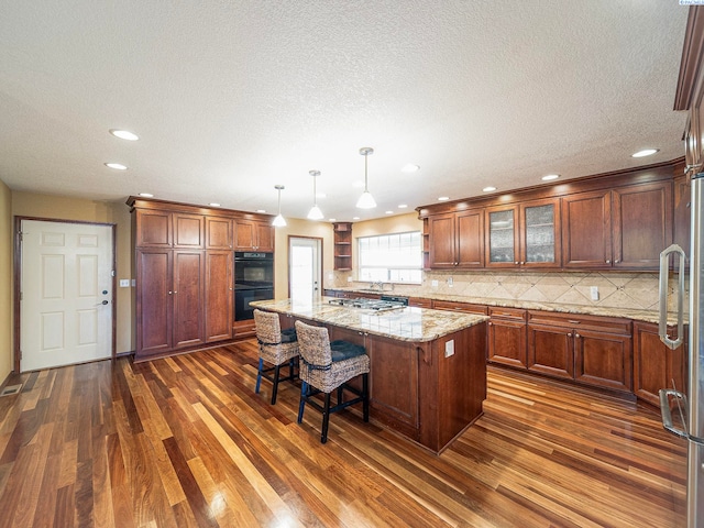 9203 Yakima Ct, Yakima, WA 98908 - kitchen with stainless steel appliances, dark wood finished floors, a kitchen island, decorative backsplash, and recessed lighting