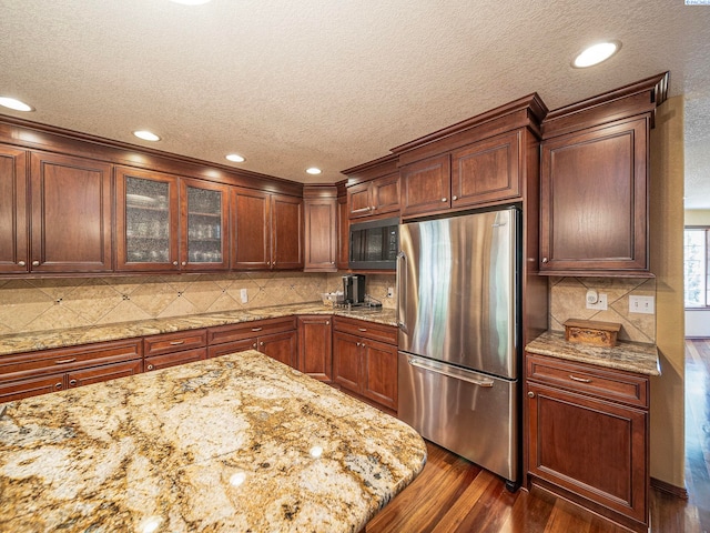9203 Yakima Ct, Yakima, WA 98908 - kitchen with freestanding refrigerator, a textured ceiling, dark wood-type flooring, glass insert cabinets, and recessed lighting