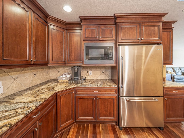 9203 Yakima Ct, Yakima, WA 98908 - kitchen with freestanding refrigerator, built in microwave, decorative backsplash, light stone counters, and a textured ceiling