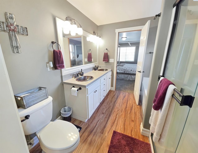 full bathroom with double vanity, a sink, toilet, and wood finished floors