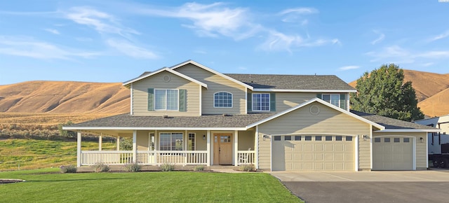 view of front facade featuring driveway, roof with shingles, an attached garage, covered porch, and a front lawn