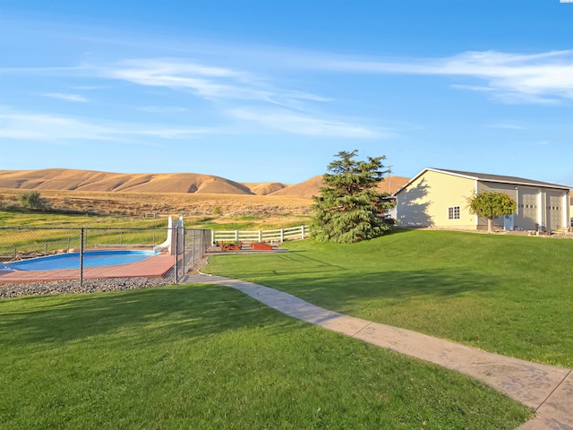 view of yard with a rural view, fence, and a mountain view