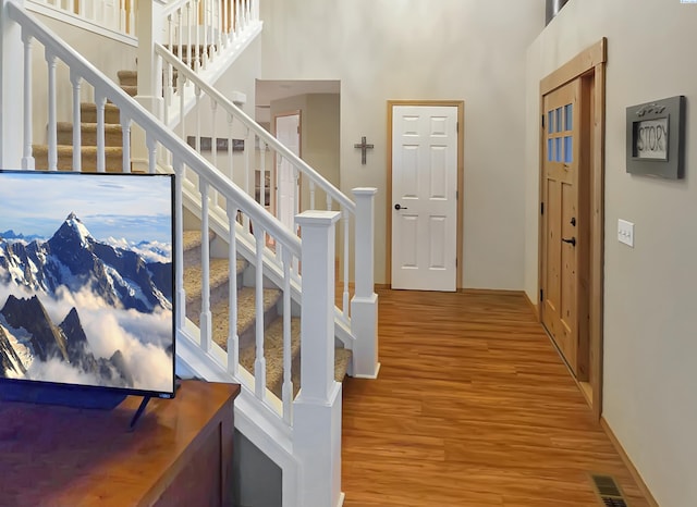 foyer featuring stairs, visible vents, a high ceiling, and wood finished floors