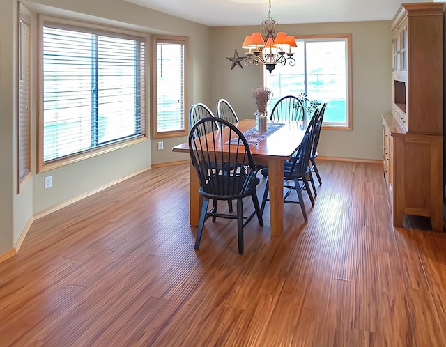 dining room with a chandelier, light wood-type flooring, and baseboards