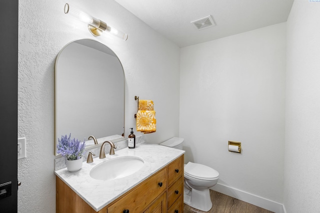 bathroom with vanity, toilet, and wood-type flooring