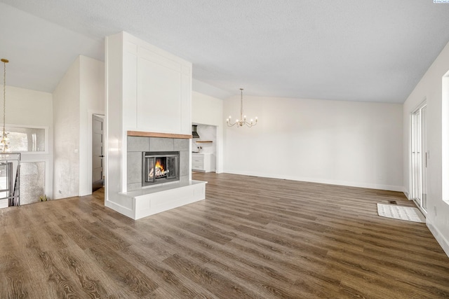 unfurnished living room featuring a tiled fireplace, lofted ceiling, a chandelier, and dark wood-type flooring