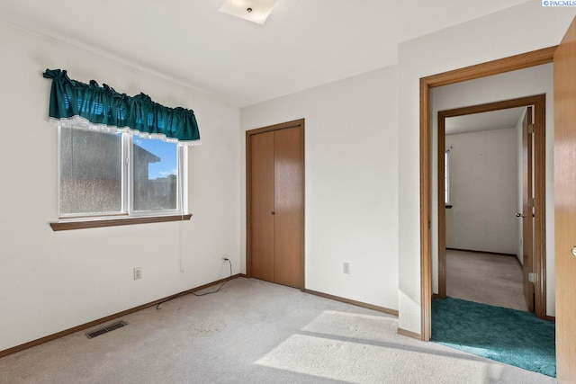 unfurnished bedroom with light carpet and a closet