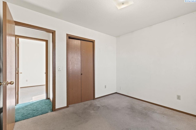 unfurnished bedroom featuring light colored carpet, a textured ceiling, and a closet