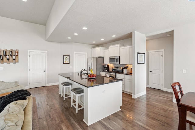 6624 Recurve Rd, Pasco, WA 99301 - kitchen with stainless steel appliances, a kitchen bar, open floor plan, dark wood-style floors, and recessed lighting