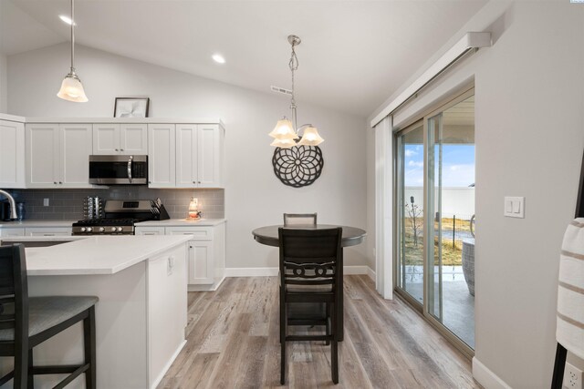 kitchen featuring decorative light fixtures, a breakfast bar area, stainless steel appliances, light countertops, and white cabinets