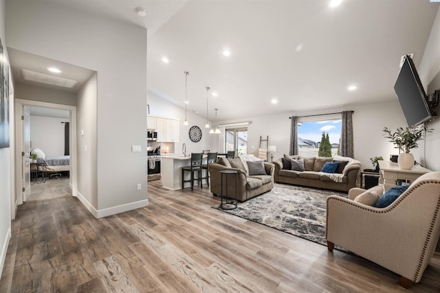 living area with baseboards, high vaulted ceiling, wood finished floors, and recessed lighting