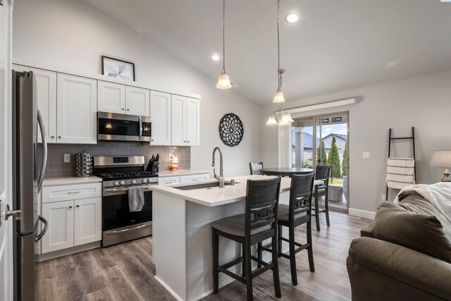 kitchen with pendant lighting, light countertops, appliances with stainless steel finishes, open floor plan, and a sink