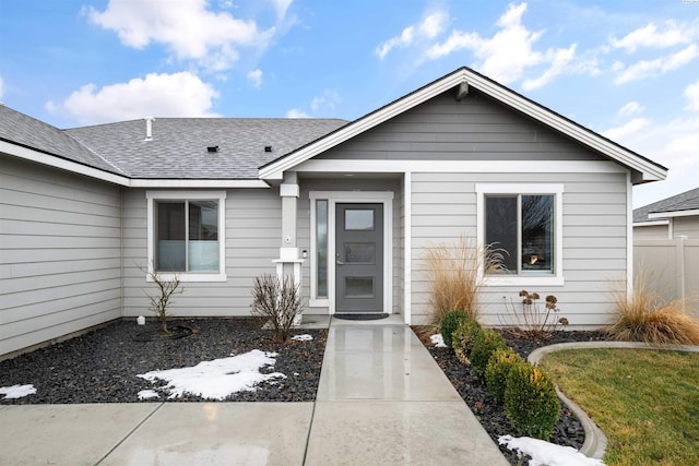 property entrance with roof with shingles and fence