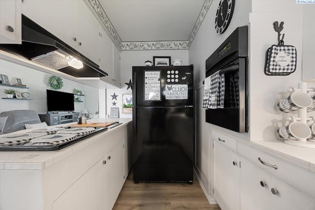 736 E 5th Ave, Kennewick, WA 99336 - kitchen with black appliances, extractor fan, light wood-style floors, and white cabinetry