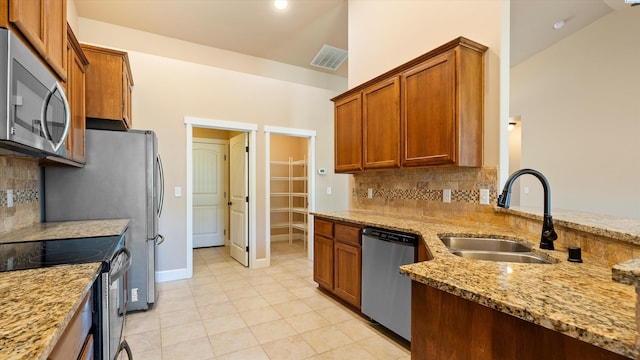 1867 S Fescue St, Kennewick, WA 99338 - kitchen with stainless steel appliances, light stone countertops, backsplash, brown cabinets, and lofted ceiling
