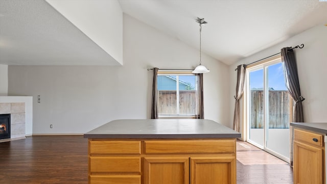 5704 Taft Dr, Pasco, WA 99301 - kitchen with wood finished floors, vaulted ceiling, a tile fireplace, hanging light fixtures, and dark countertops