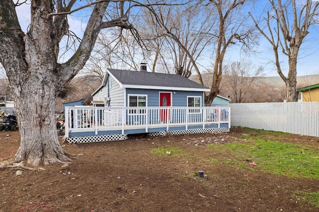 view of front of home featuring a shingled roof, fence, and a deck