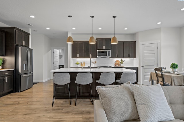 kitchen with tasteful backsplash, open floor plan, light countertops, light wood-style floors, and stainless steel appliances