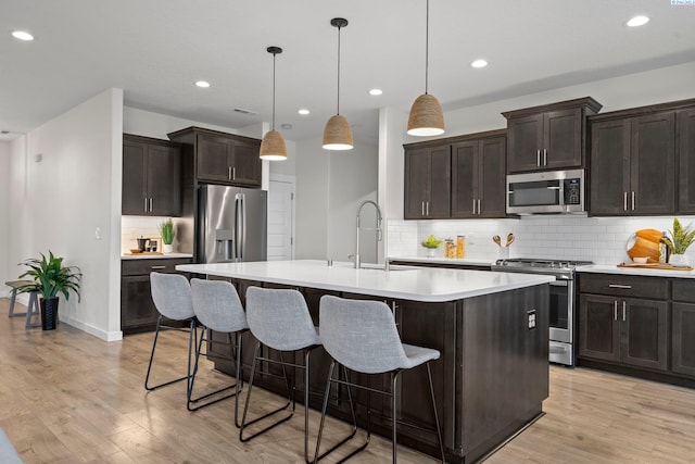 kitchen featuring a sink, appliances with stainless steel finishes, light wood-style flooring, and light countertops