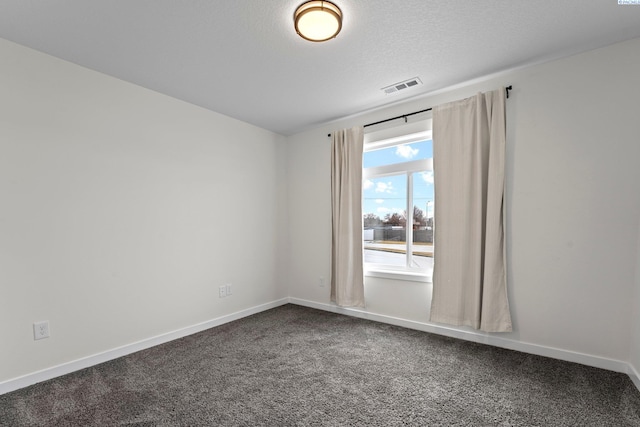 unfurnished room with baseboards, visible vents, dark colored carpet, and a textured ceiling