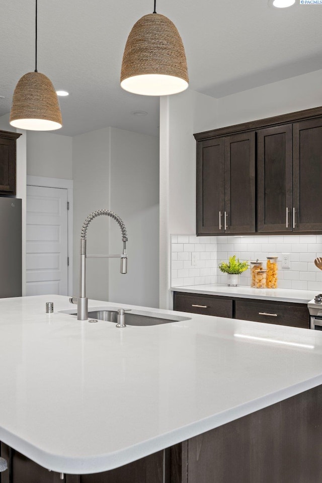 kitchen featuring a sink, decorative backsplash, dark brown cabinetry, and light countertops