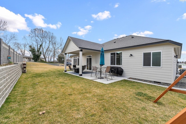 back of property with a patio area, a lawn, roof with shingles, and fence