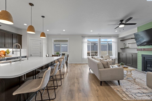 living area with a wealth of natural light, a glass covered fireplace, light wood-style flooring, and a textured ceiling