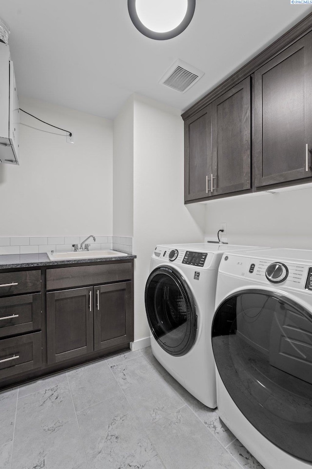 clothes washing area featuring washing machine and clothes dryer, visible vents, cabinet space, marble finish floor, and a sink