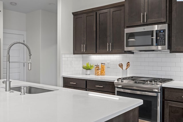 kitchen featuring a sink, stainless steel appliances, dark brown cabinetry, light countertops, and backsplash