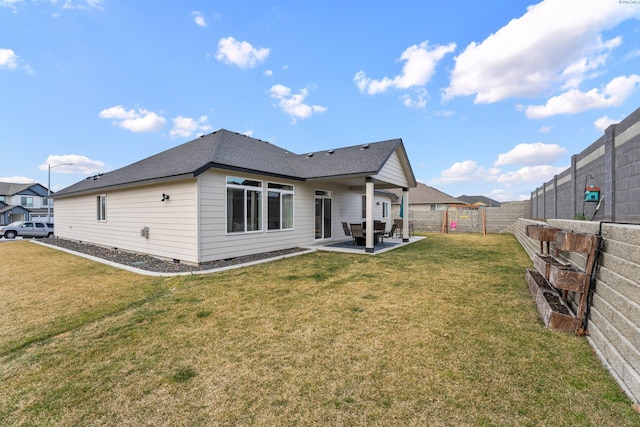 rear view of property with roof with shingles, a fenced backyard, crawl space, a patio area, and a lawn