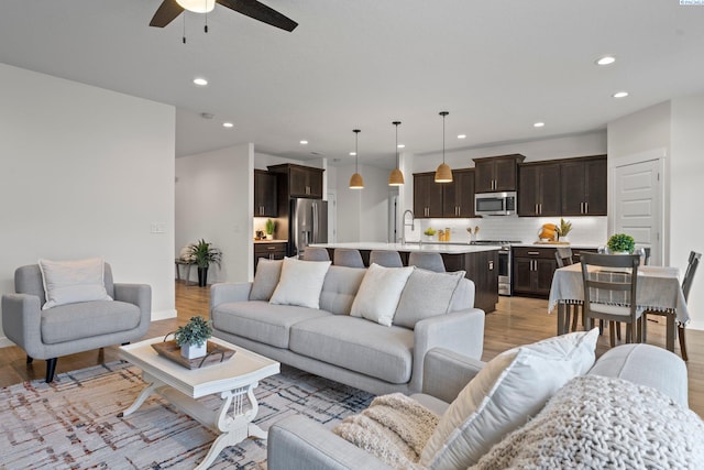 living area featuring recessed lighting, baseboards, ceiling fan, and light wood finished floors