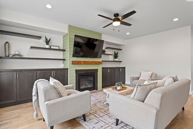 living area featuring recessed lighting, light wood-type flooring, a ceiling fan, and a fireplace